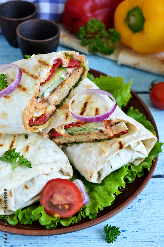 shawarma Lavash with chicken, tomatoes, lettuce and peppers on a blue background