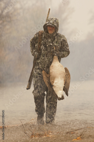 Goose Hunter In Rain Carrying Dead Goose photo