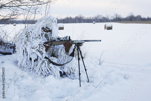 Varmint Hunter In Ghillie Snow Suit With Rifle On Bipod in winter photo