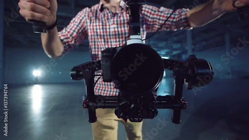 The operator with the camera mounted on the three-axis handheld gimbal electronic stabilizator runs up directly to the camera photo