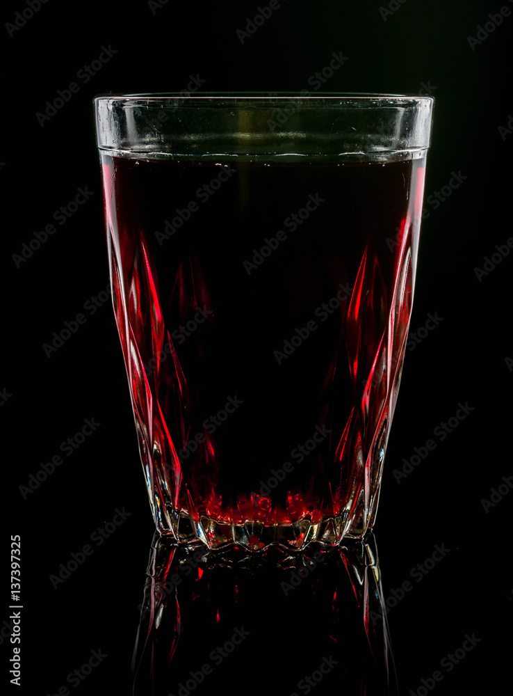 A glass with red drink on a dark background. A glass with red drink on a dark background.