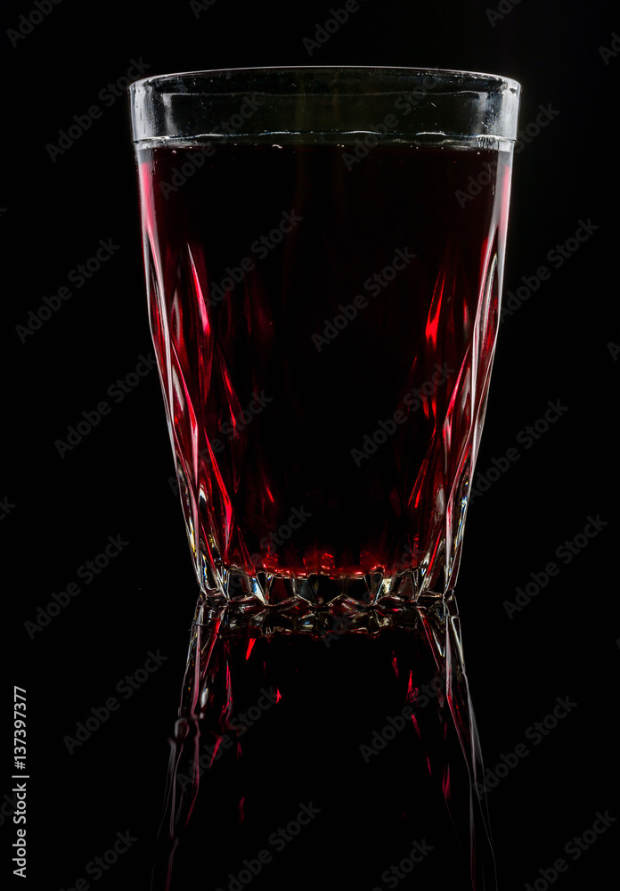 A glass with red drink on a dark background. A glass with red drink on a dark background.