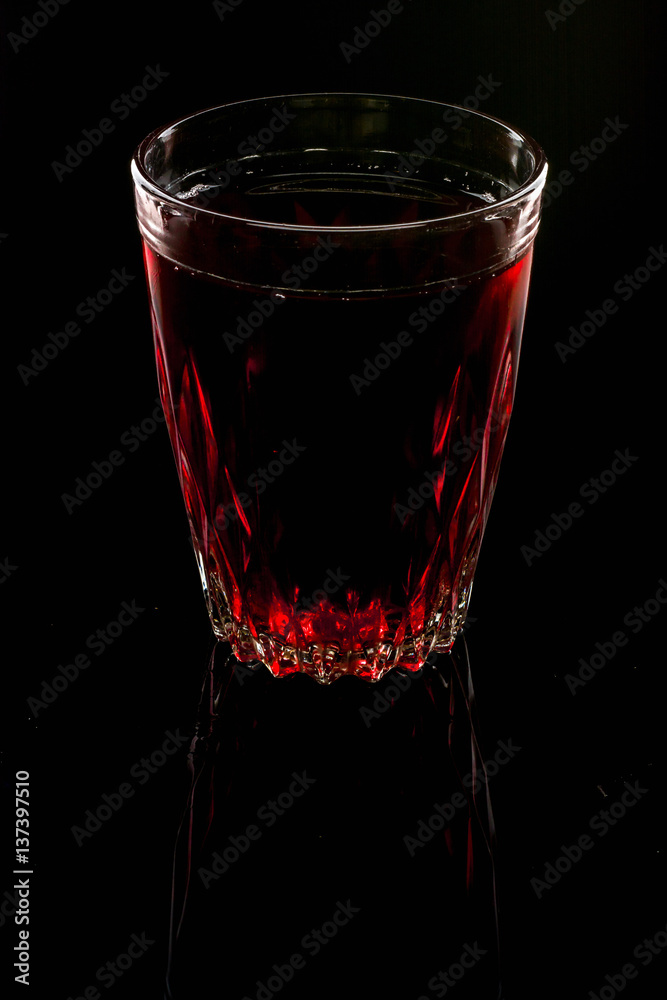 A glass with red drink on a dark background. A glass with red drink on a dark background.