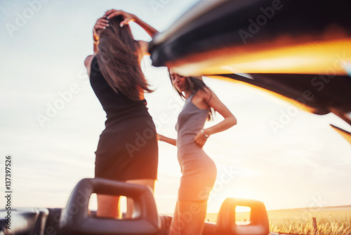 Girls gladly posing next to a black car © standret