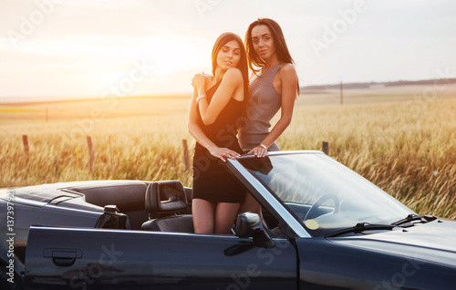 Two women in a black car on the roadside roads. © standret