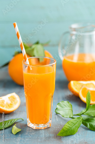 Orange juice in glass and fresh fruits with leaves on wooden background, vitamin drink or cocktail