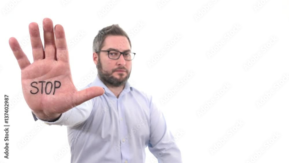 Handsome man rising hand showing word STOP on palm disapproval expression indoor white background medium close up, soft focused businessman Handsome man rising hand showing word STOP on palm disapproval expression indoor white background medium close up, soft focused businessman