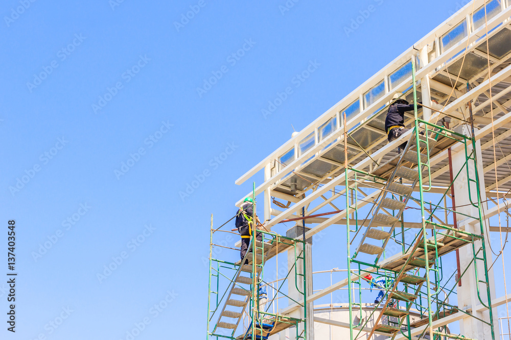 Construction workers working on scaffolding, Man Working on the Working at height with blue sky at construction site