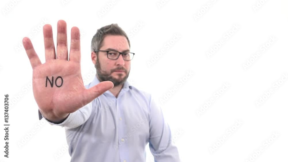 Serious businessman rising hand showing stop with word NO on palm disapproval expression indoor white background medium close up, soft focused man Serious businessman rising hand showing stop with word NO on palm disapproval expression indoor white background medium close up, soft focused man