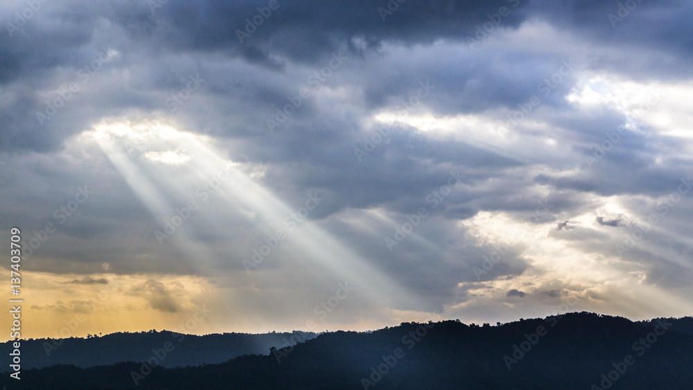 Sunset over beautiful blue sky with sun shining through clouds