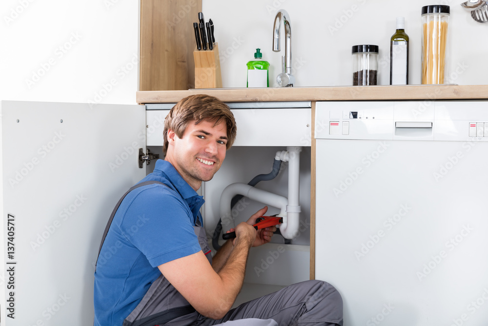 Obraz premium Male Plumber Fixing Sink Pipe
