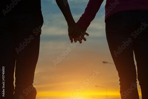 young couple holding hands on the road at sunset.