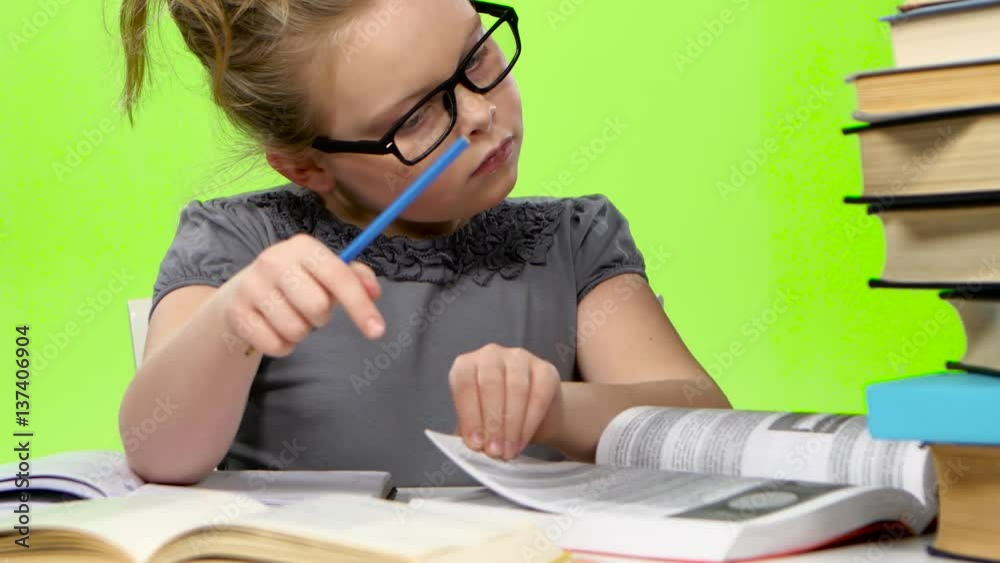 Little girl in glasses looking in books information. Green screen Little girl in glasses looking in books information. Green screen