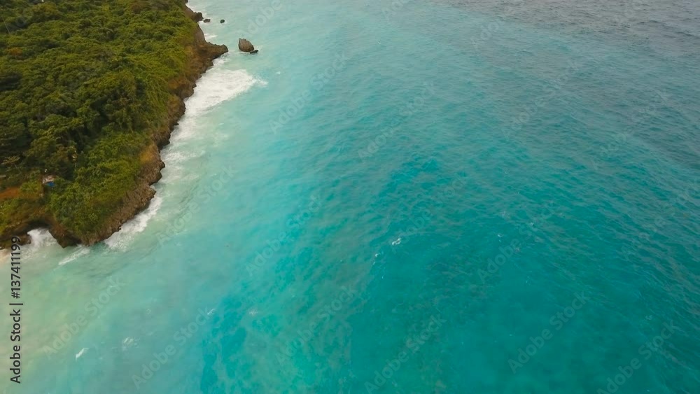 Rocky shore on the tropical sea with the rainy cloud. Aerial view:Stormy weather on island.Rocks in sea in cloudy gloomy weather. Big waves crushing on the shore of a tropical island with palm trees Rocky shore on the tropical sea with the rainy cloud. Aerial view:Stormy weather on island.Rocks in sea in cloudy gloomy weather. Big waves crushing on the shore of a tropical island with palm trees