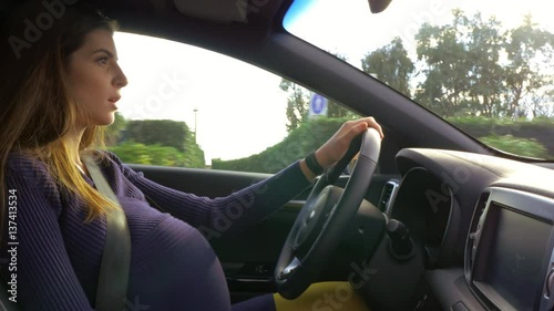 Beautiful pregnant woman driving car starting to feel sick