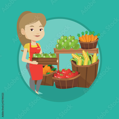 Supermarket worker with box full of apples.