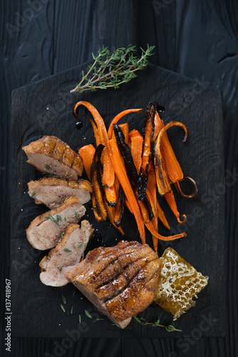 Top view of fried duck breast fillet with baked carrot and honey