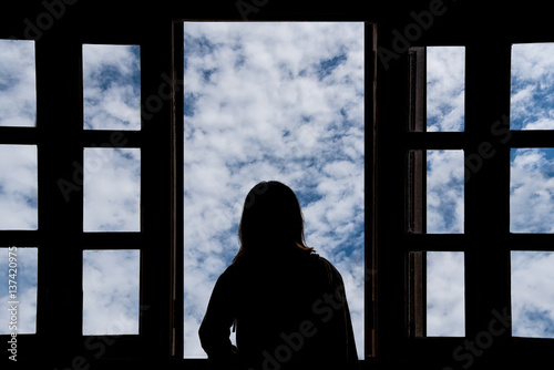 Silhouette young woman in the hotel, looking blue sky through the window © midobun2014