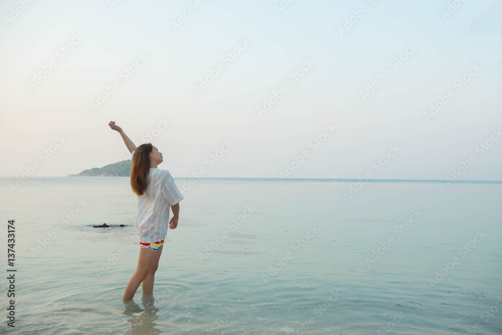 Happy woman standing arms outstretched  and enjoy life on the beach at Sea