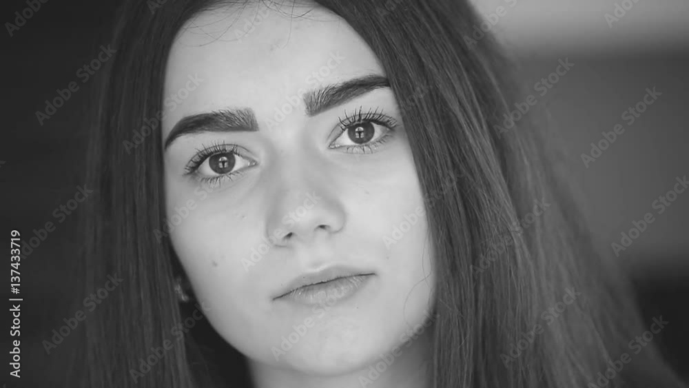 The girl with long hair and brown eyes raises his eyes and looks into the camera. The girl with long hair and brown eyes raises his eyes and looks into the camera.