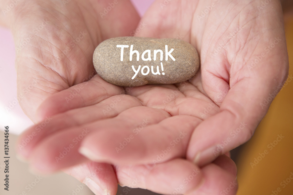 closeup of womans hands holding stone with words thank you closeup of womans hands holding stone with words thank you