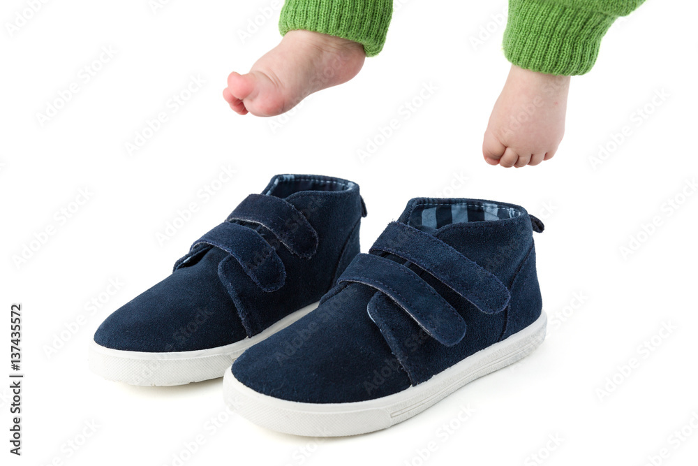 Baby feet with too big blue child shoes isolated on white