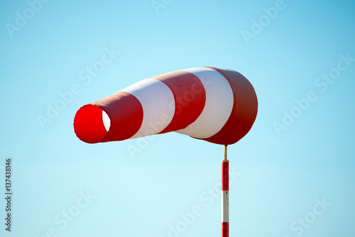 Horizontally flying windsock (wind vane) due to high wind. Blue sky in the background. Success concept. photo