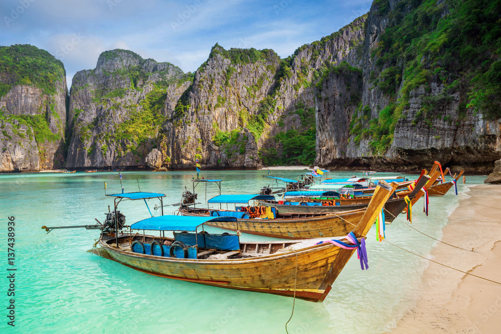 Thailand sea beach view round with steep limestone hills with many traditional longtail boats parking
