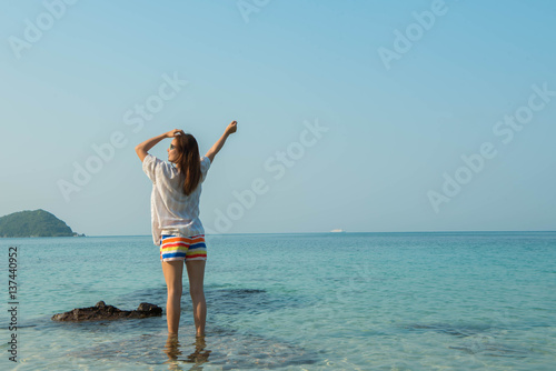 Happy woman standing arms outstretched on the beach at Sea