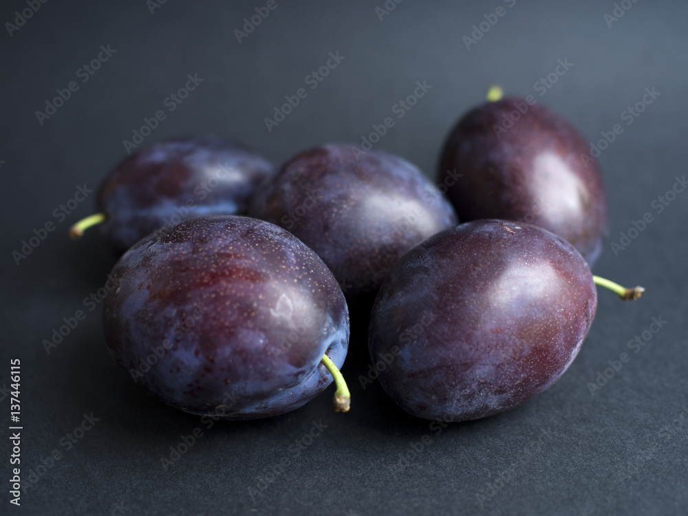 Purple plums isolated on dark background
