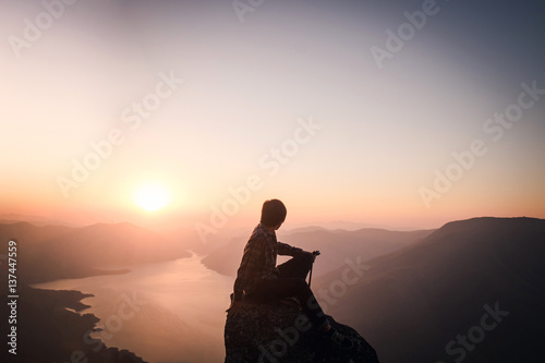 Traveler watching amazing sunset. Silhouette of the young man on the mountain