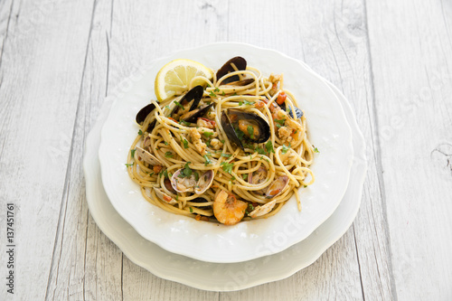Spaghetti with seafood in white ceramic plate on wooden background
