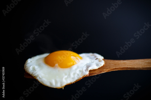 Fried egg with a wooden spoon