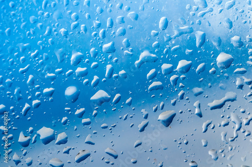 Several water drops on transparent glass and on blue background
