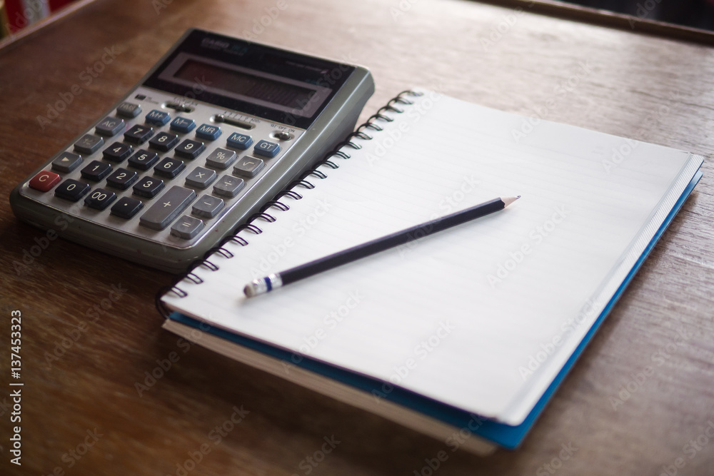 Blank notebook pencil and calculator on wood table Blank notebook pencil and calculator on wood table