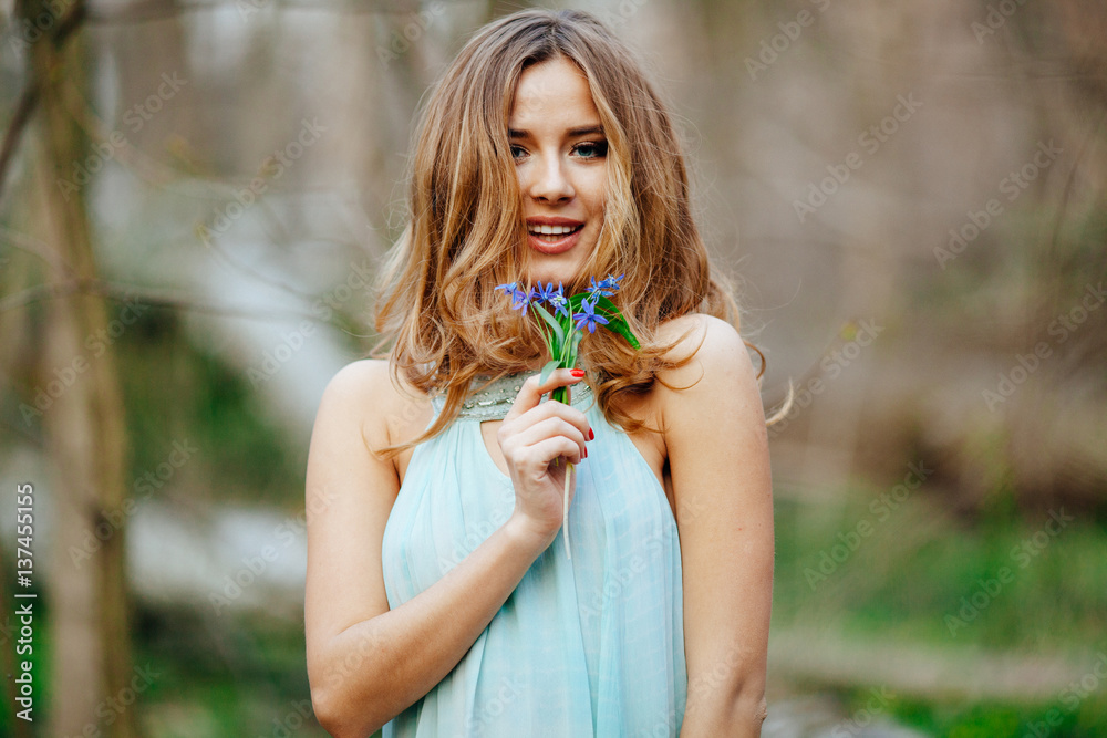 attractive model in blue dress smell snowdrop flowers in the spring forest attractive model in blue dress smell snowdrop flowers in the spring forest