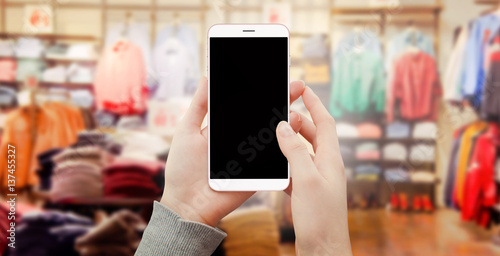 Women holding modern smartphone with black screen in store. Smartphone mockup for emarket and fashion concept