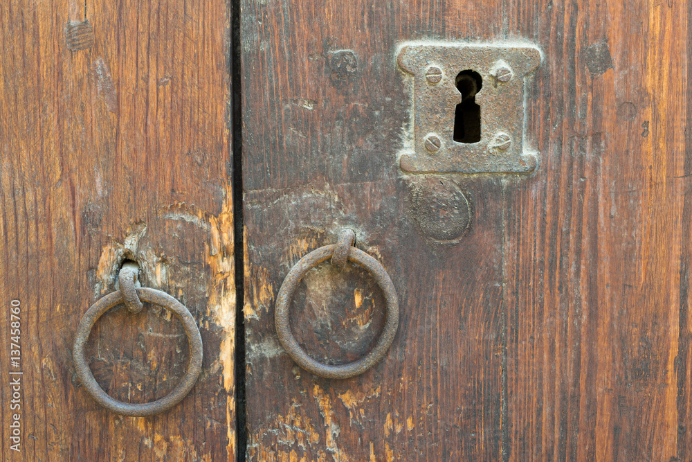 Two rusty iron ring door knobs and keyhole over an old wooden grunge door