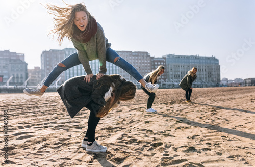Four friends playing leapfrog on the beach photo