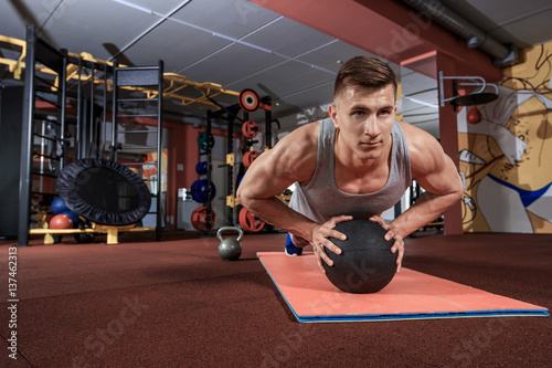 Attractive male athlete performing push-ups on medicine ball