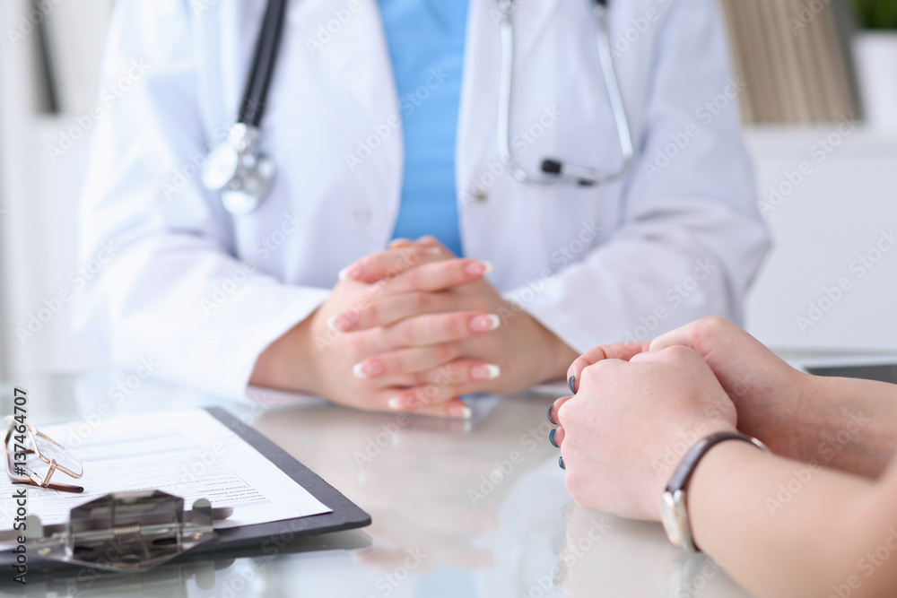 Close up of a doctor and patient hands discussing something while sitting at the table . Medicine and health care concept Close up of a doctor and patient hands discussing something while sitting at the table . Medicine and health care concept