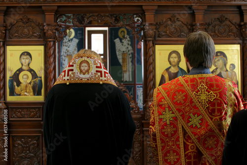 Orthodox bishop and archdeacon praying in front of altar