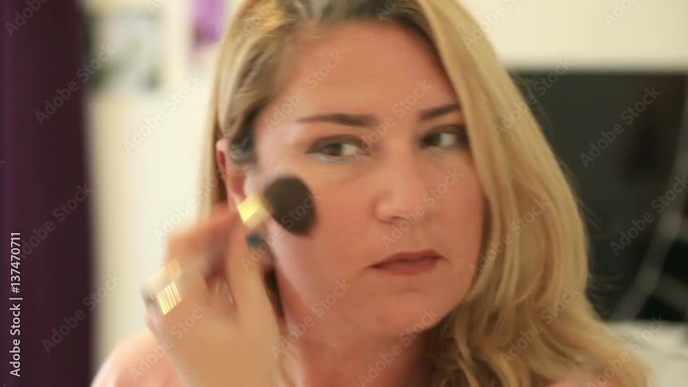 Reflection of woman face in mirror using make up brush Reflection of woman face in mirror using make up brush