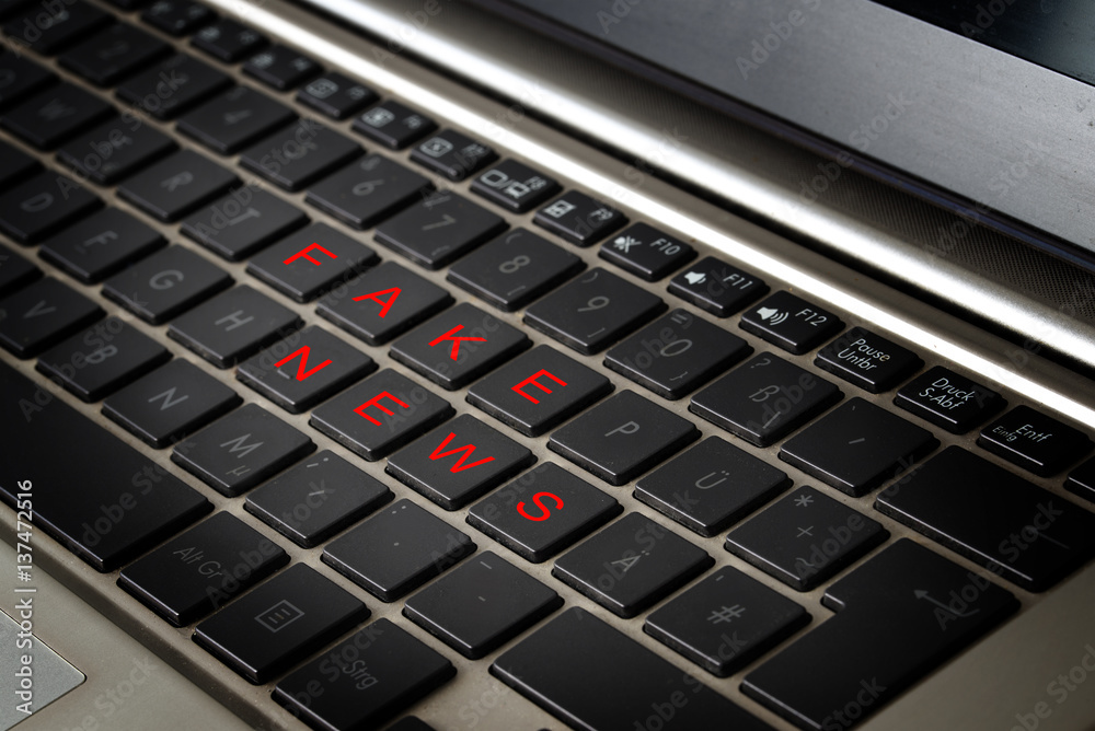 Computer laptop keyboard with the words FAKE NEWS in red letters on black keys
