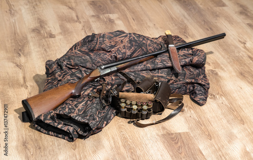 old double-barreled shotgun, camouflage jacket, knife in scabbard, amunition belt and cartridges for shotgun photo