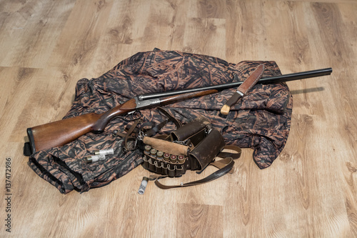 old double-barreled shotgun, camouflage jacket, knife in scabbard, amunition belt and cartridges for shotgun photo