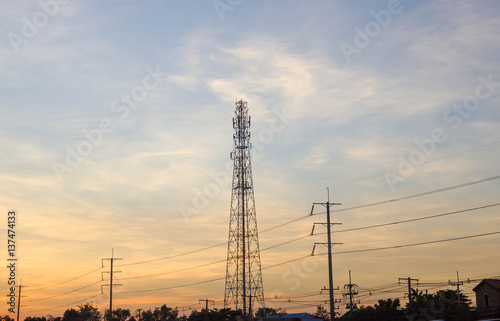 Electricity pylon silhouetted against blue sky wih cloud background. High voltage tower