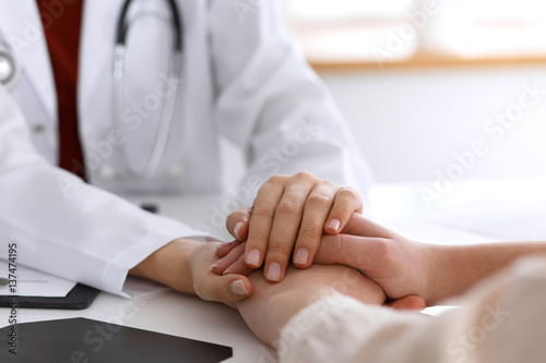 Hand of doctor  reassuring her female patient. Medical ethics and trust concept