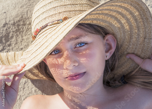 A girl laying on the sand wearing a sunhat; Tarifa, Cadiz, Andalusia, Spain