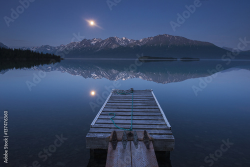 Boat dock with a full moon rising over the Chigmit Mountains at Lake Clark in Lake Clark National Park and Preserve, Alaska. photo